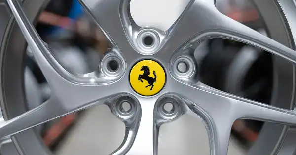 Cerchio in lega Ferrari 812 con stemma centrale giallo in magazzino, con altri cerchi sfocati sullo sfondo.