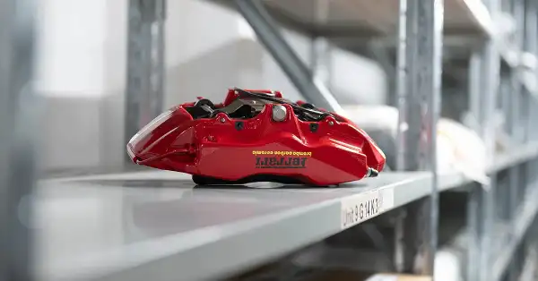 Pinza freno Brembo rossa Ferrari su uno scaffale all'interno del magazzino Eurospares.